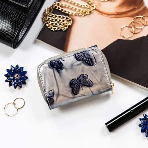 Detal srebrnego portfela damskiego Peterson – motylki i faktura skóry Detail of silver Peterson women’s wallet – butterflies and leather texture